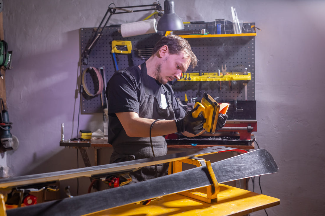 Un homme en tenue de travail, un réparateur de vêtements dans l'atelier, un service de ski réparant le ski